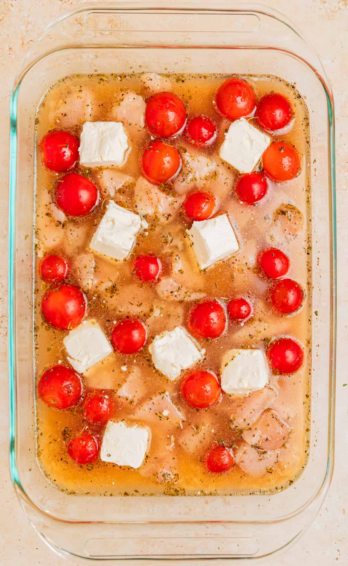 Cream cheese cubed and placed in various spots in pan.
