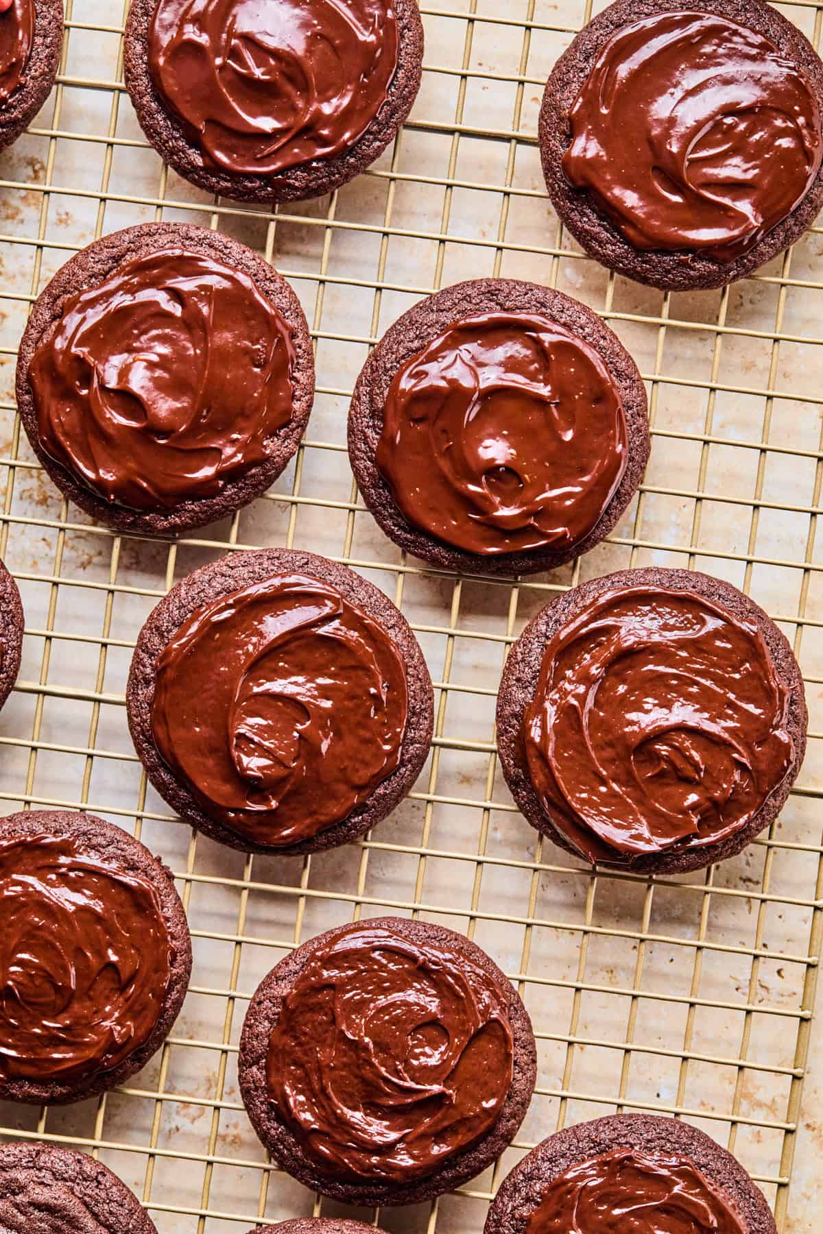 Chocolate ganache spread on cookies on cooling rack.