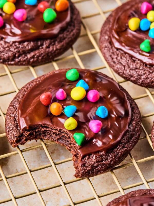 Cosmic brownie cookies on wire rack with bite taken out.