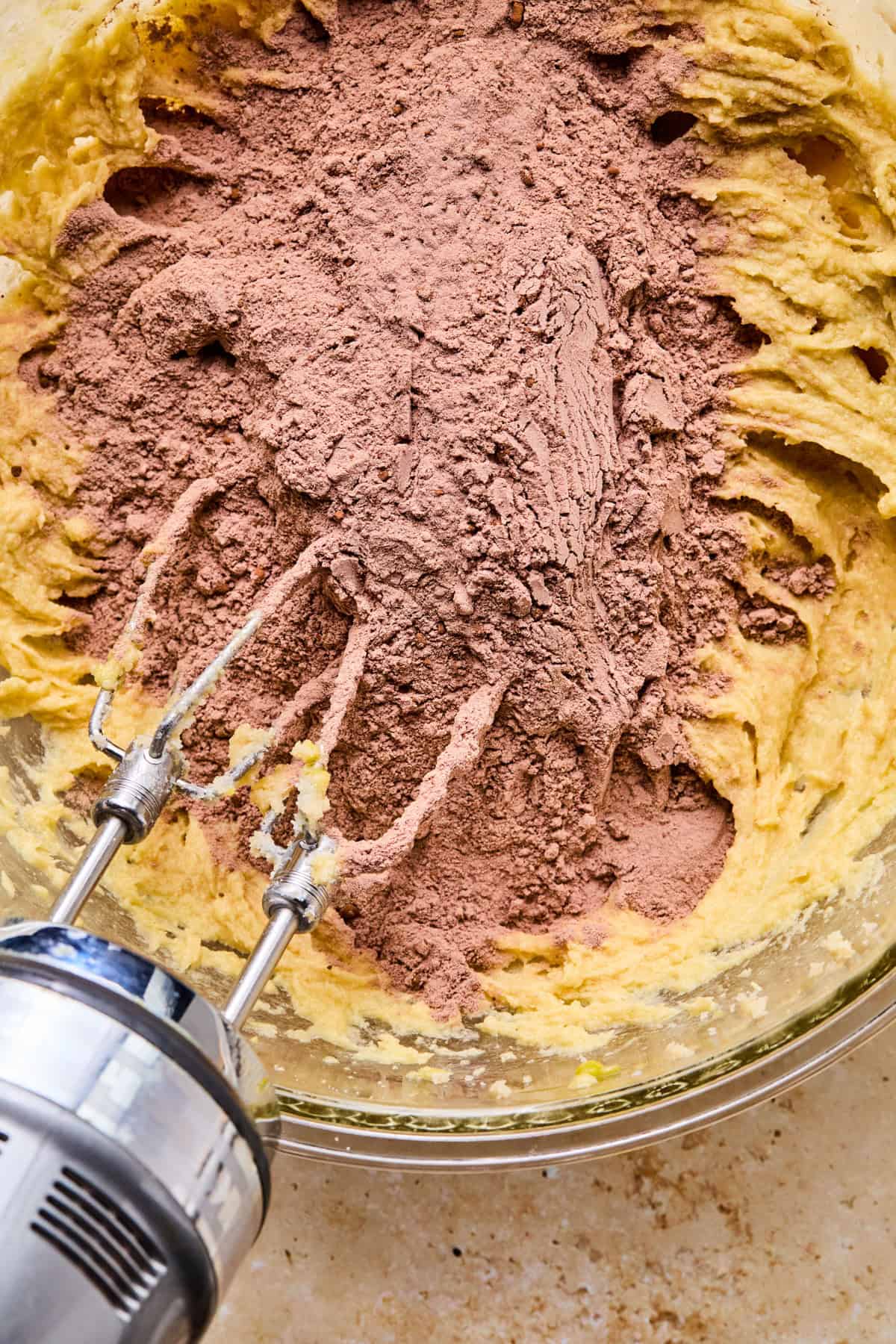 Cocoa powder added to bowl with wet ingredients.