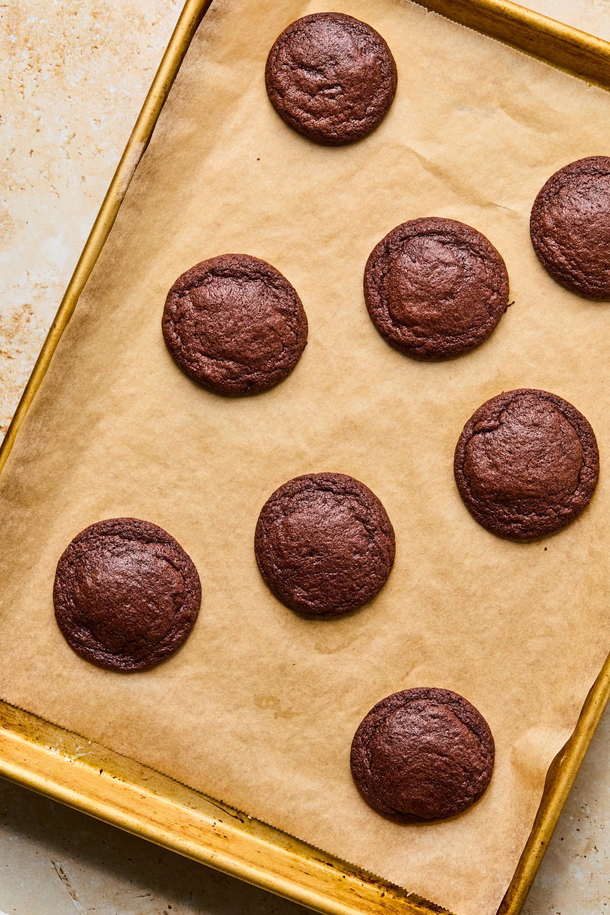 Baked chocolate cookies on cookie sheet.