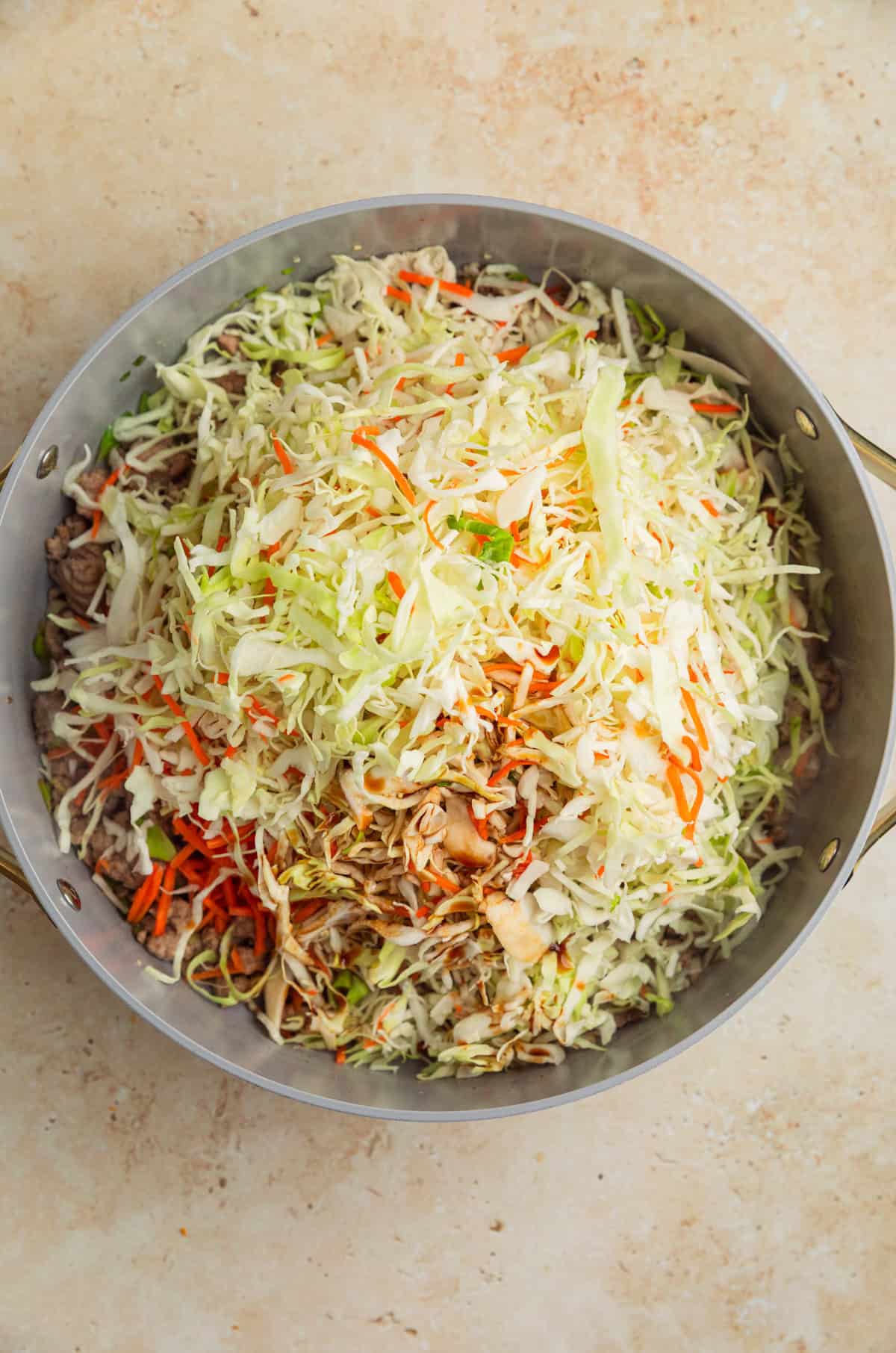 Cabbage, carrots and other ingredients added to pan with ground turkey.