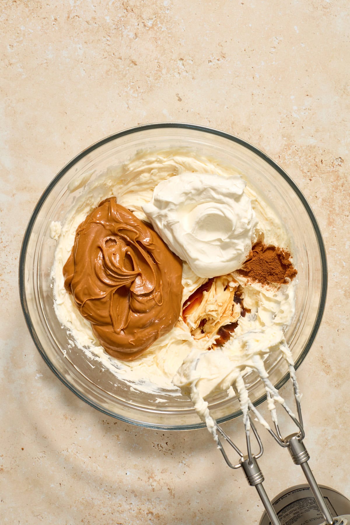 Cookie butter, sour cream, and vanilla added to bowl with cream cheese.