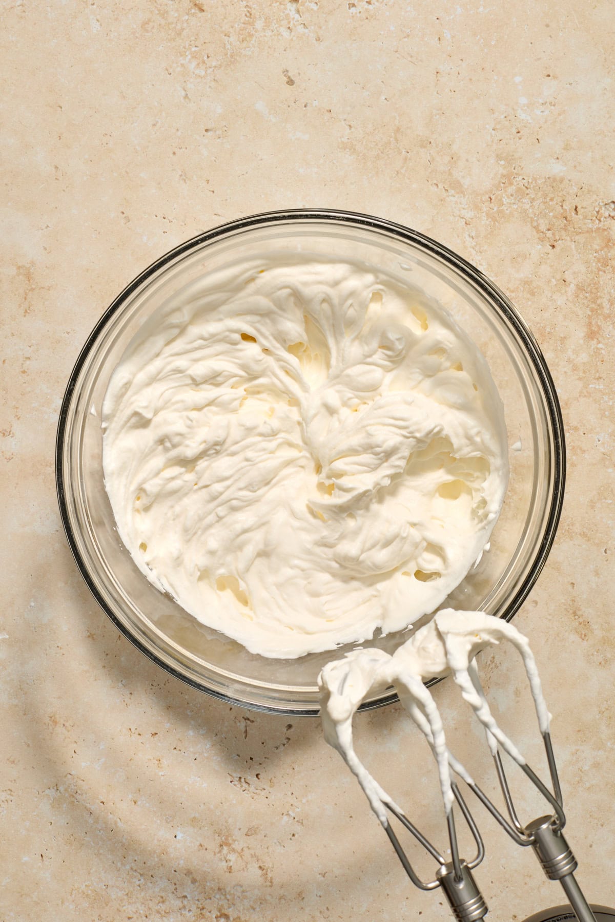 Whipped cream whipped in glass bowl with hand mixer.