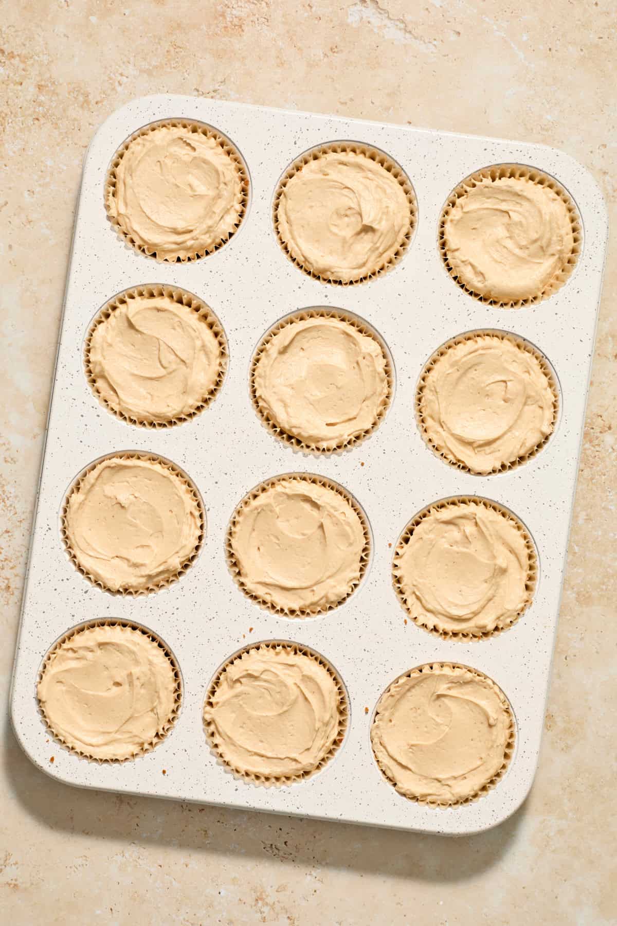 Cookie butter mini cheesecakes in muffin tin before chilling.