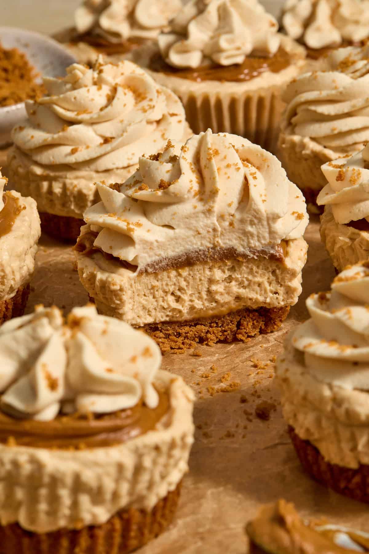No-bake mini cheesecakes topped with cookie butter whipped cream on parchment.