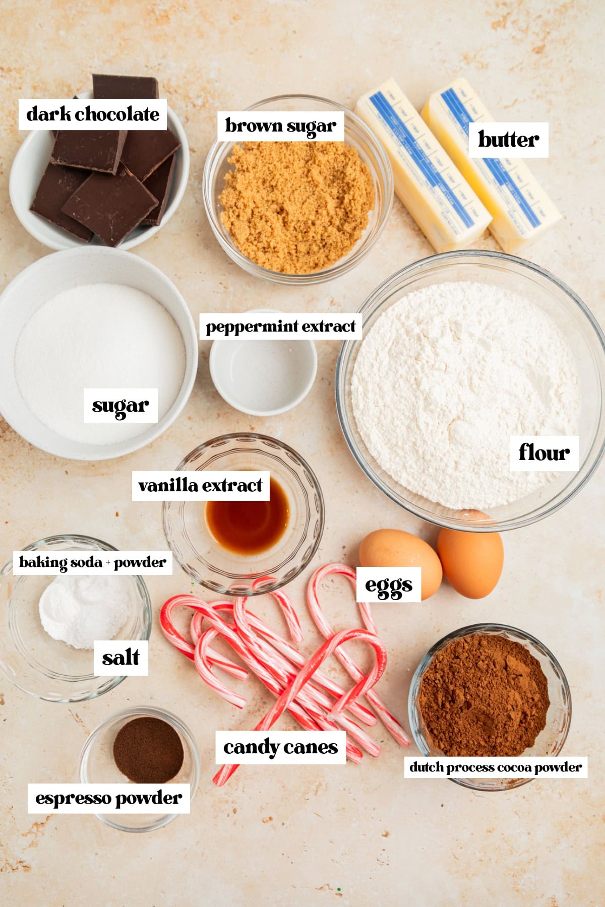 Flour, eggs, cocoa powder, espresso powder and other ingredients arranged on surface.