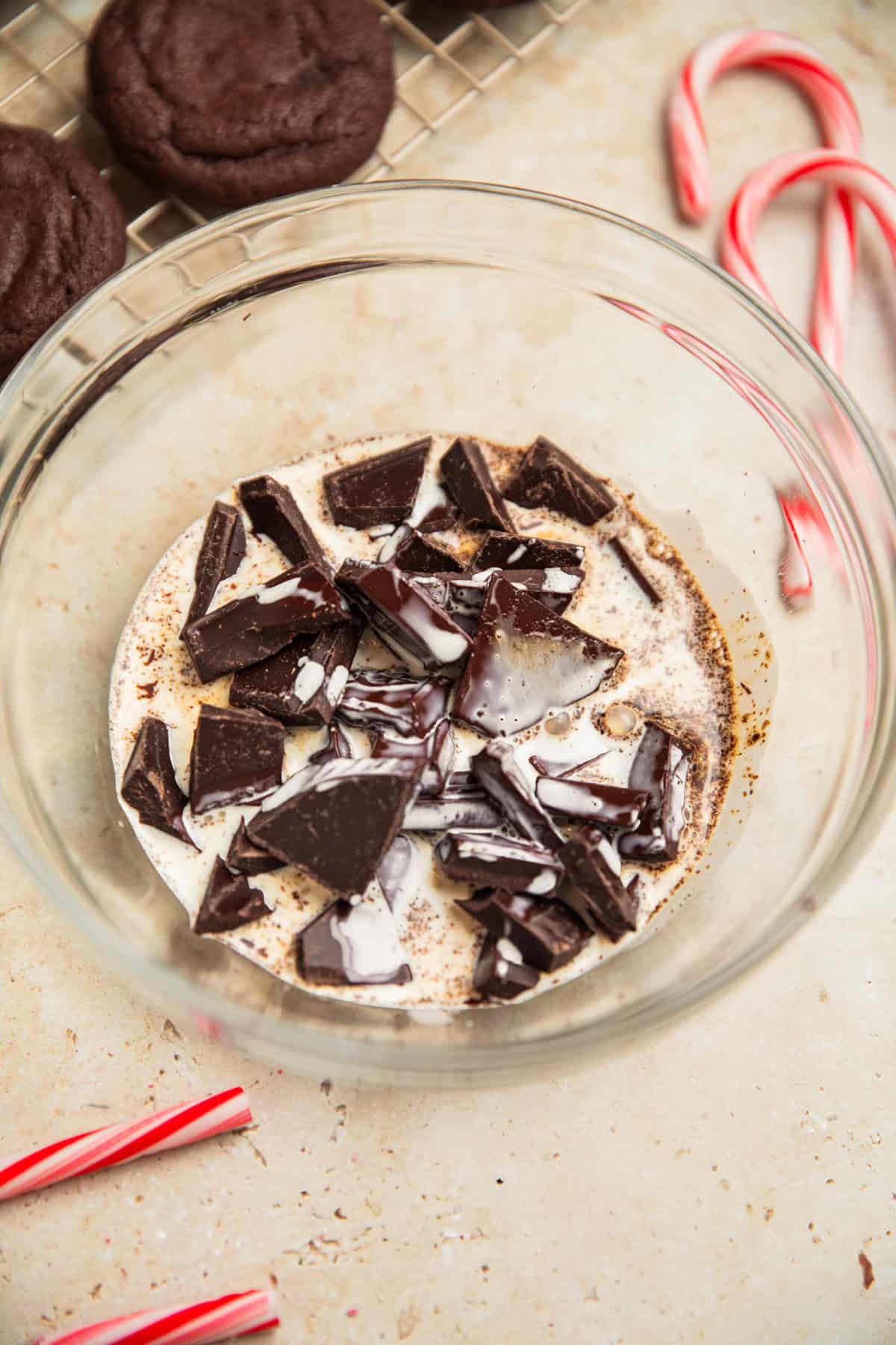 Hot cream added to chopped chocolate in bowl.