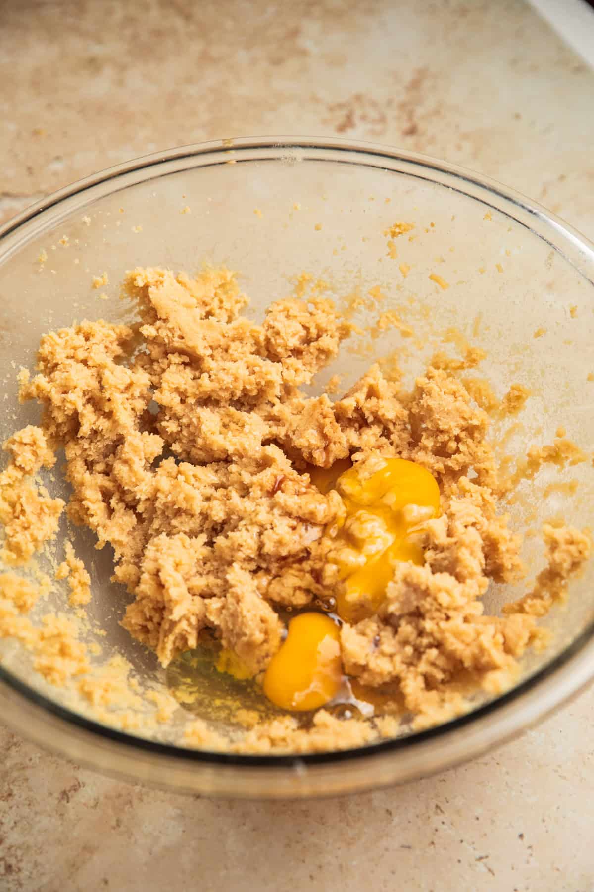 Creamed butter and sugars in mixing bowl with eggs added to the bowl.