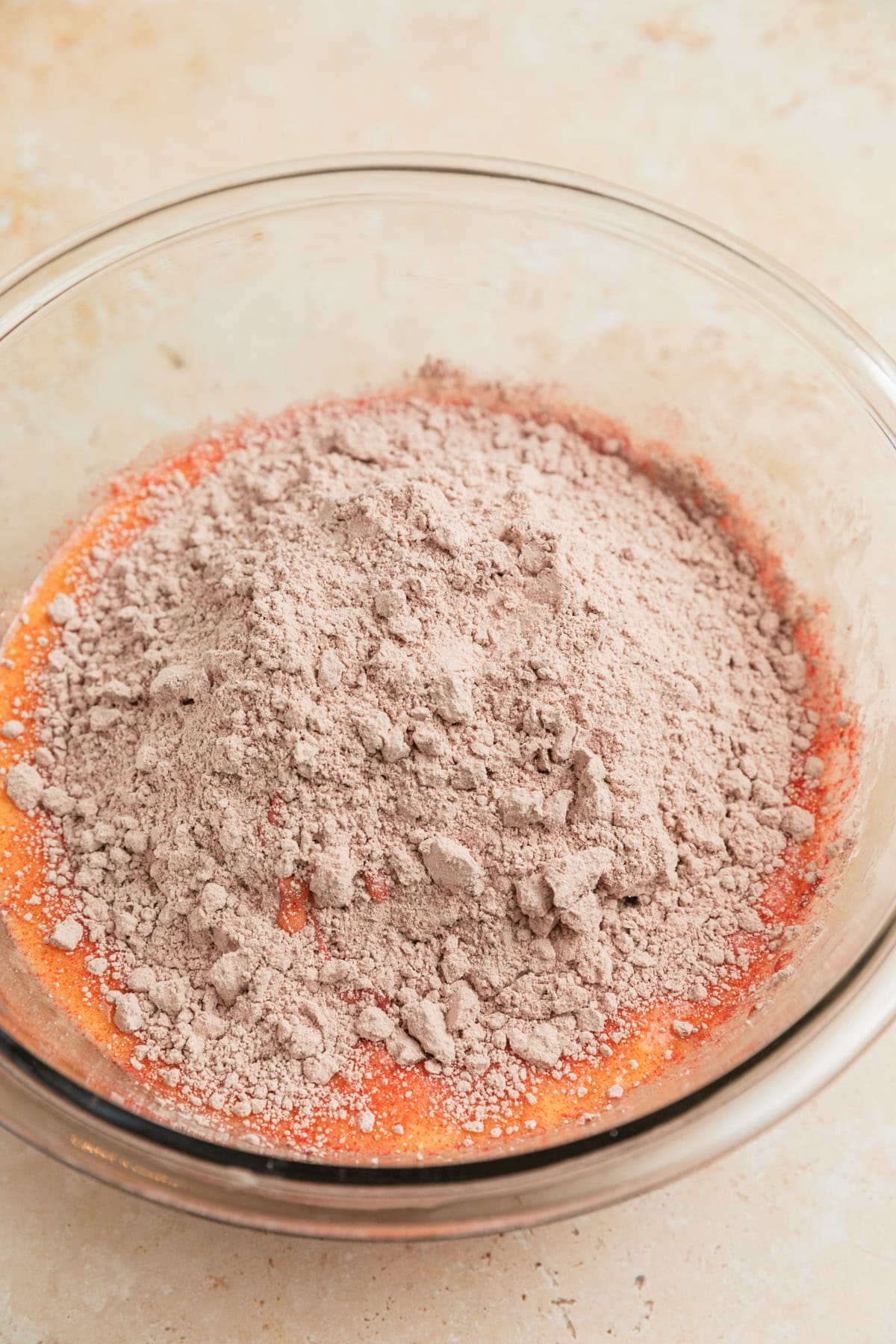 Red velvet cake mix added to bowl with eggs and butter.