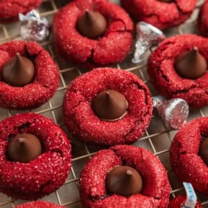 Red velvet cookies with Hershey kiss centers on wire rack.