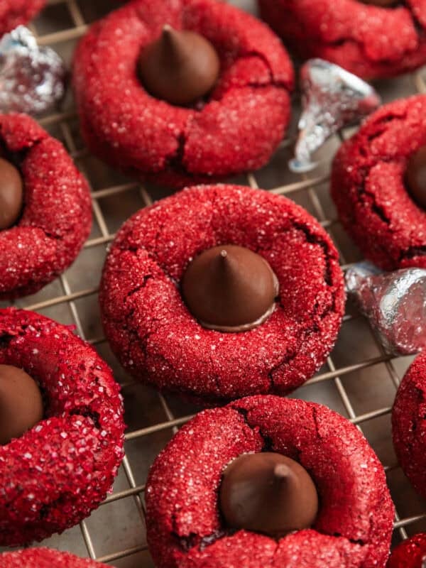 Red velvet cookies with Hershey kiss centers on wire rack.