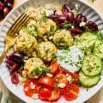 Spinach and feta turkey meatballs on plate with fork and topped with fresh herbs.