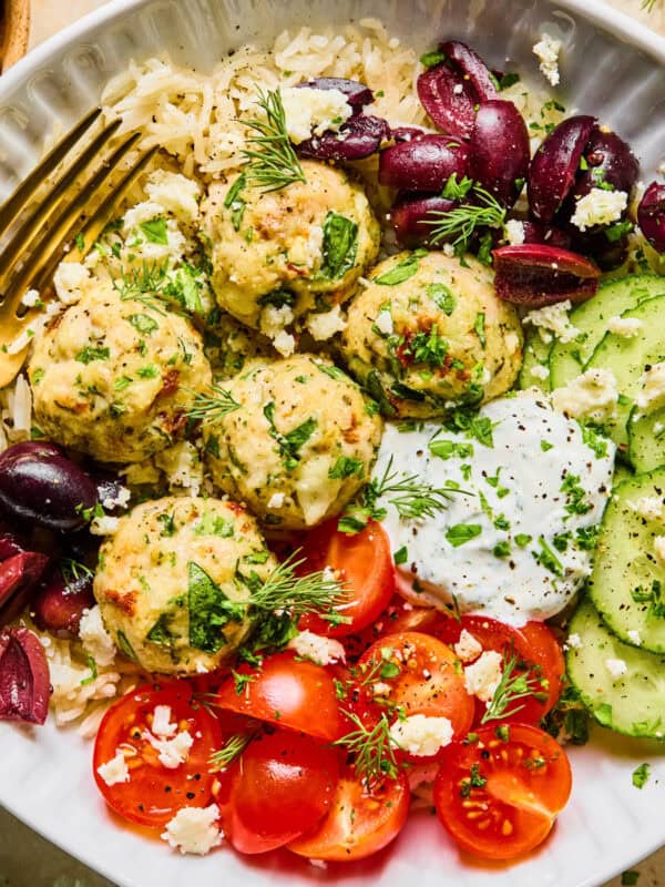 Spinach and feta turkey meatballs on plate with fork and topped with fresh herbs.
