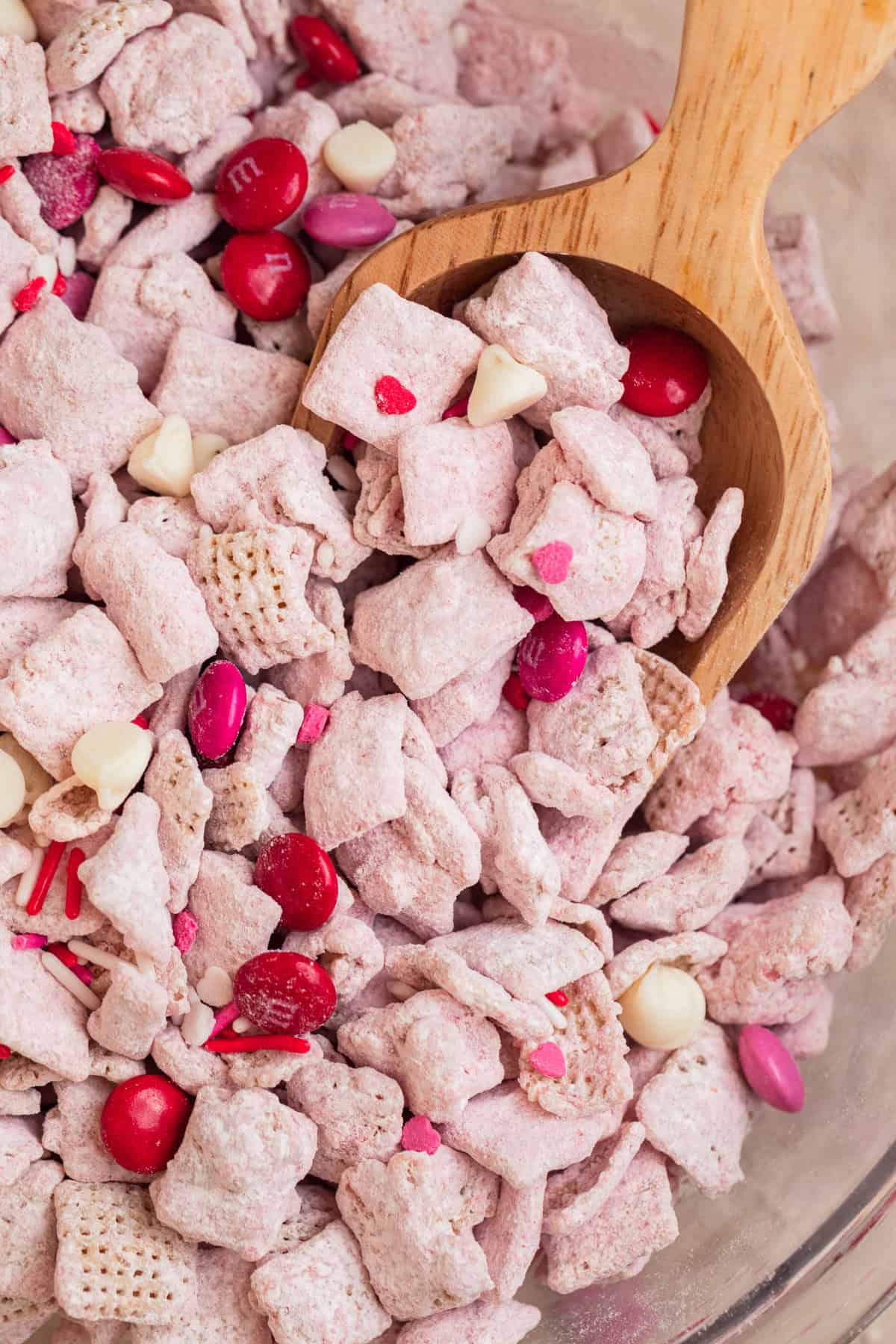 Bowl with strawberry puppy chow and wood scoop scooping into it,