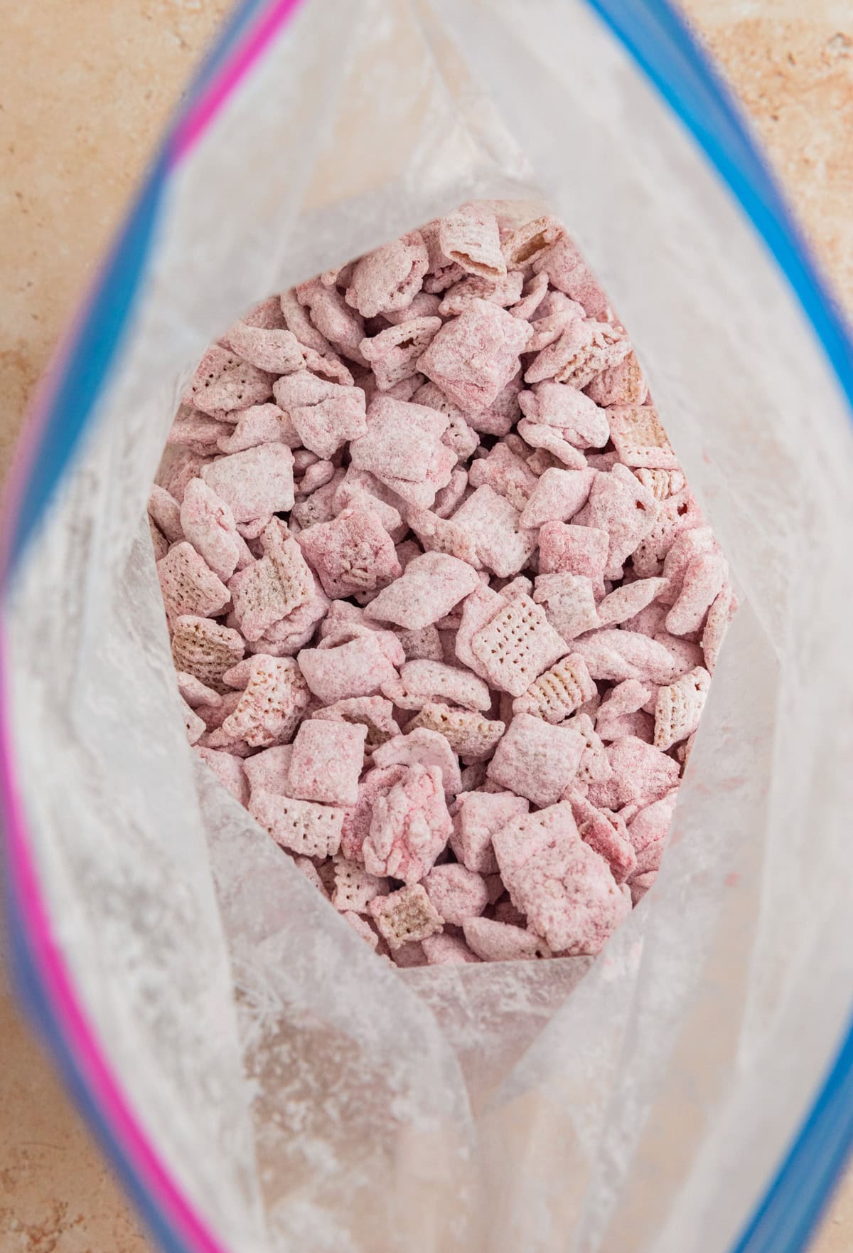 Strawberry puppy chow coated with powdered sugar in bag.