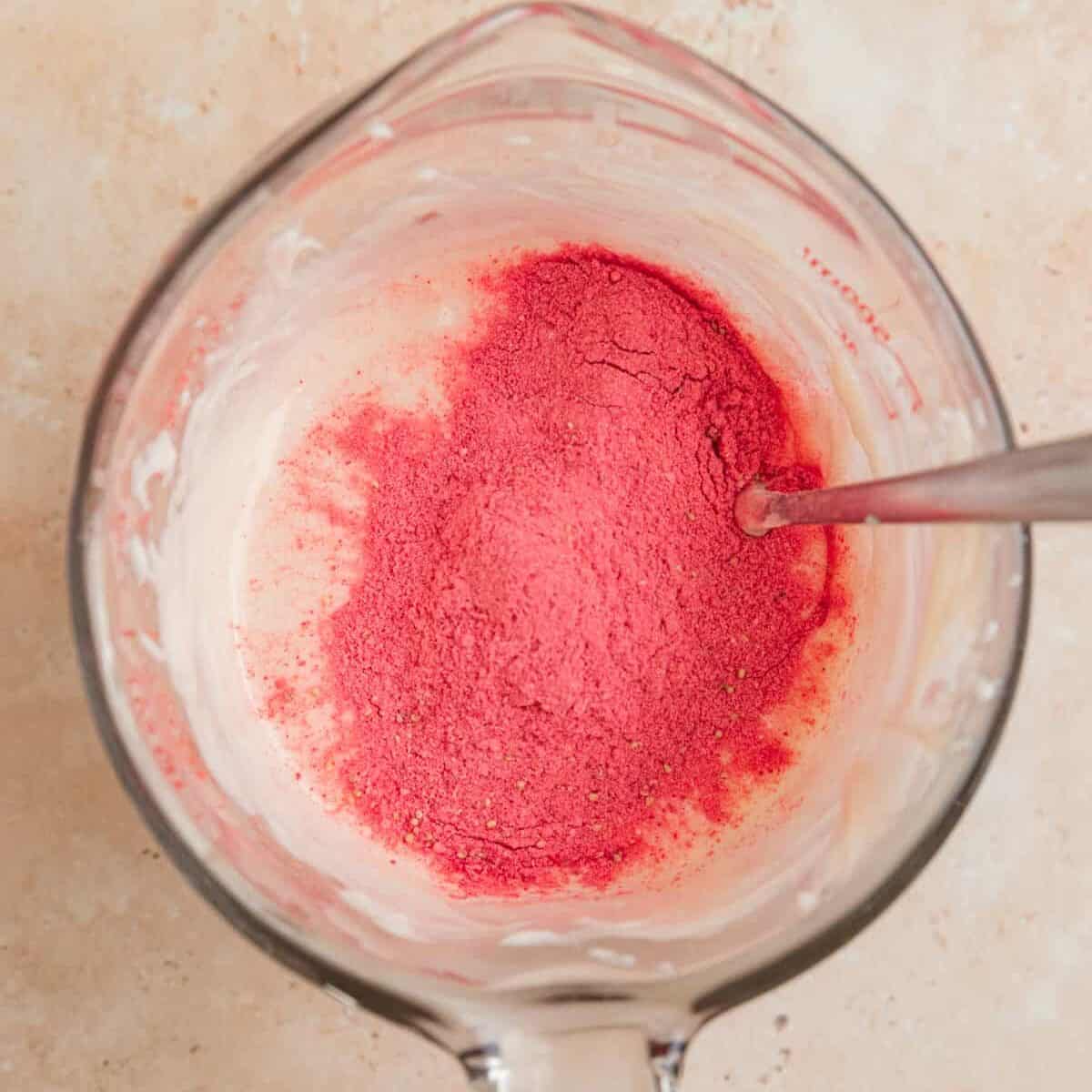 Strawberry powder in mixing cup with melted white chocolate.
