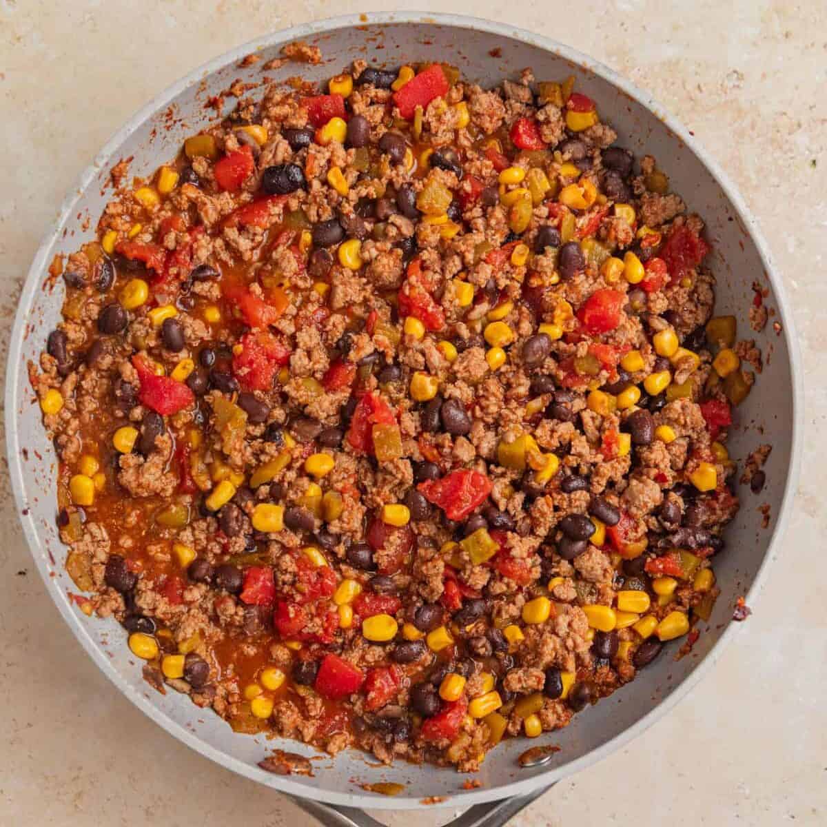 Ground turkey taco filling in skillet with corn and beans.