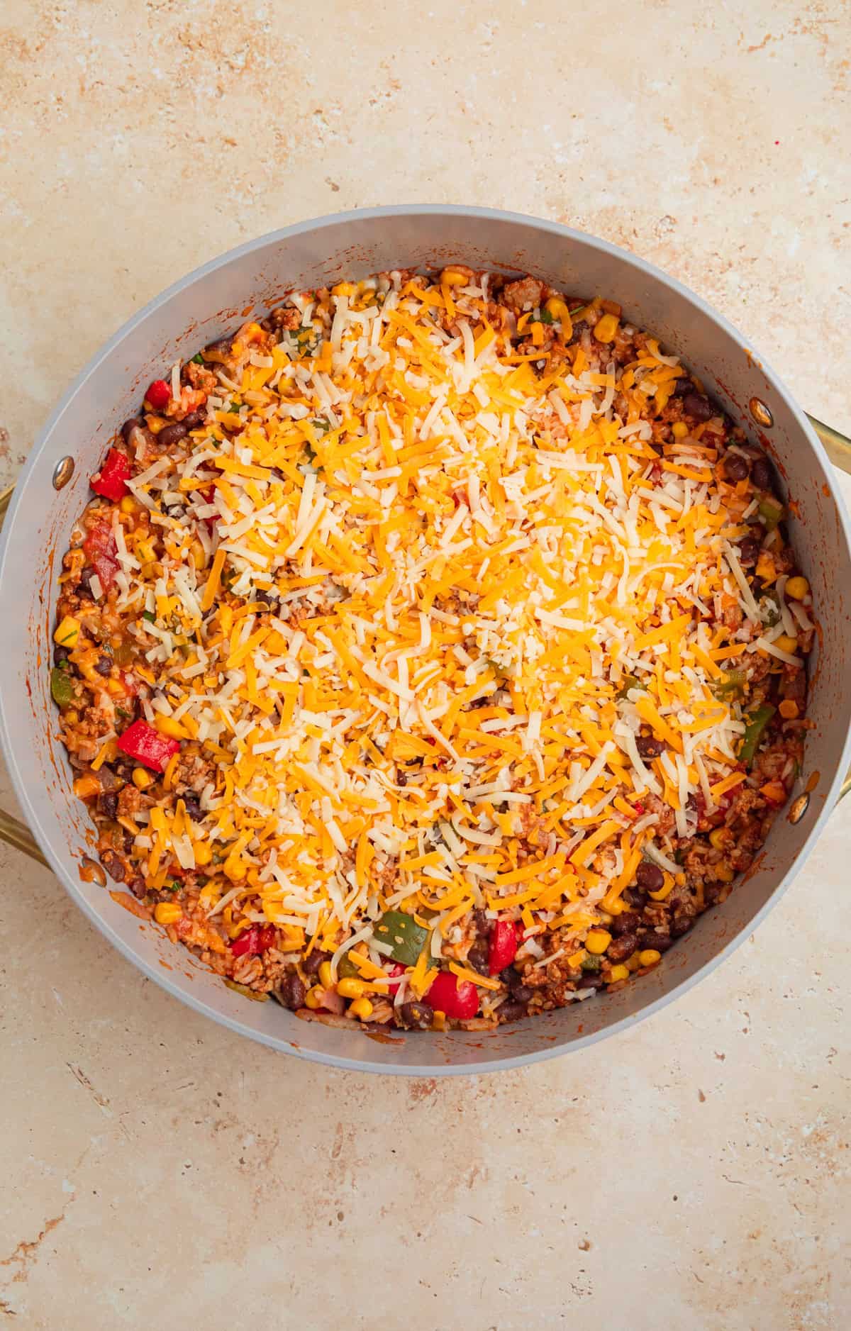 Shredded cheese sprinkled over top of taco and rice skillet.