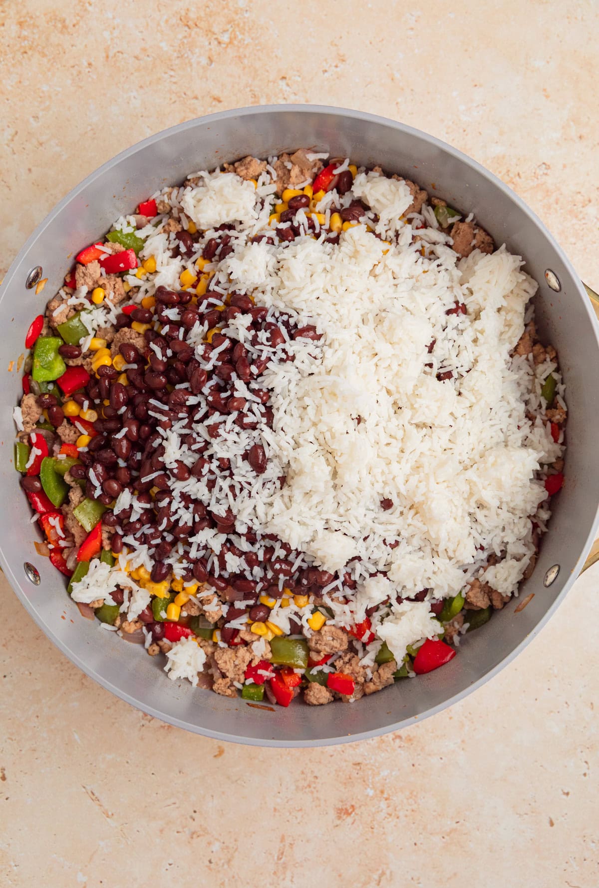 Cooked rice, black beans, tomatoes and other ingredients added to pan with browned meat.