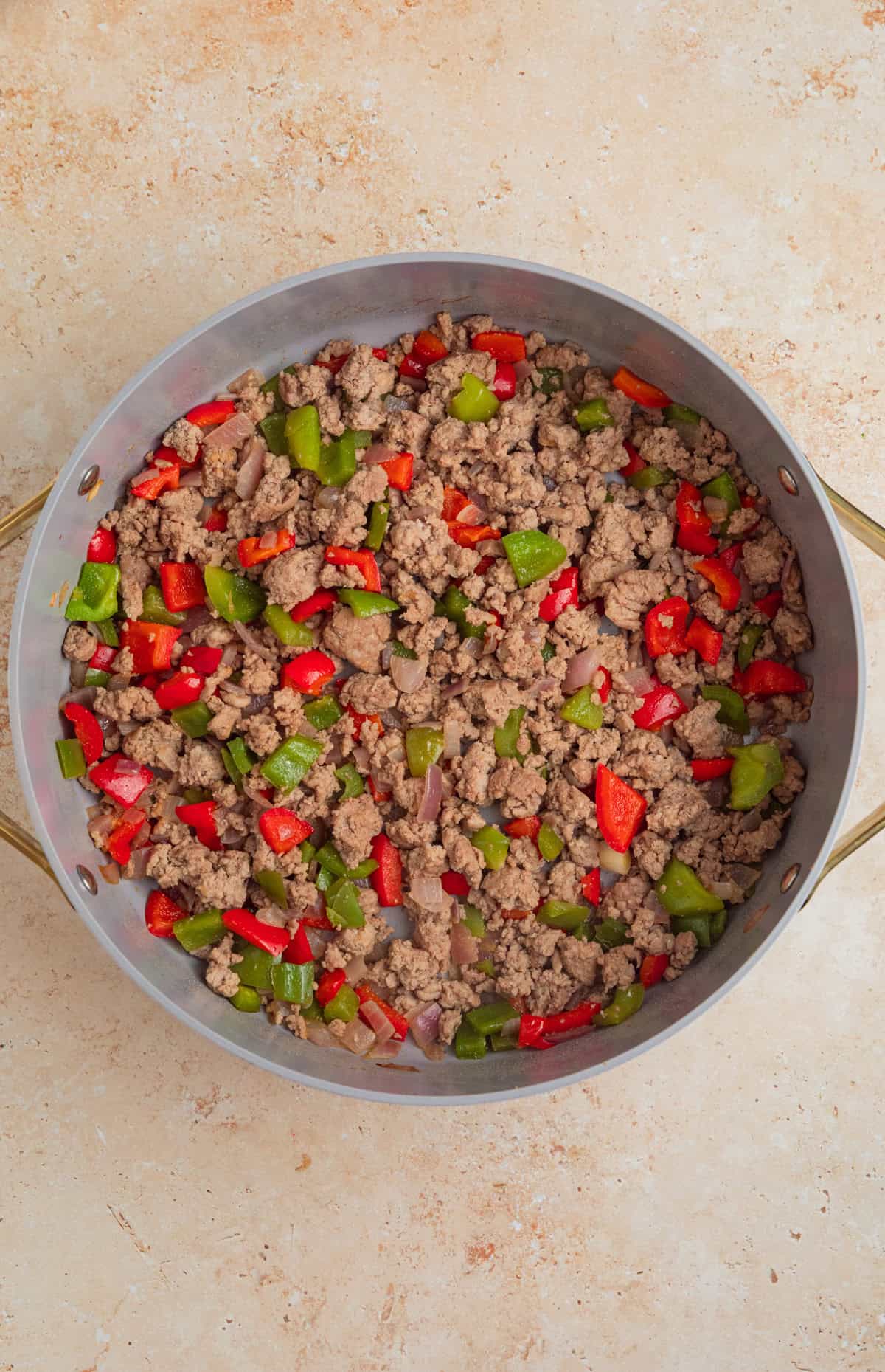 Browned turkey in pan with onions and peppers.