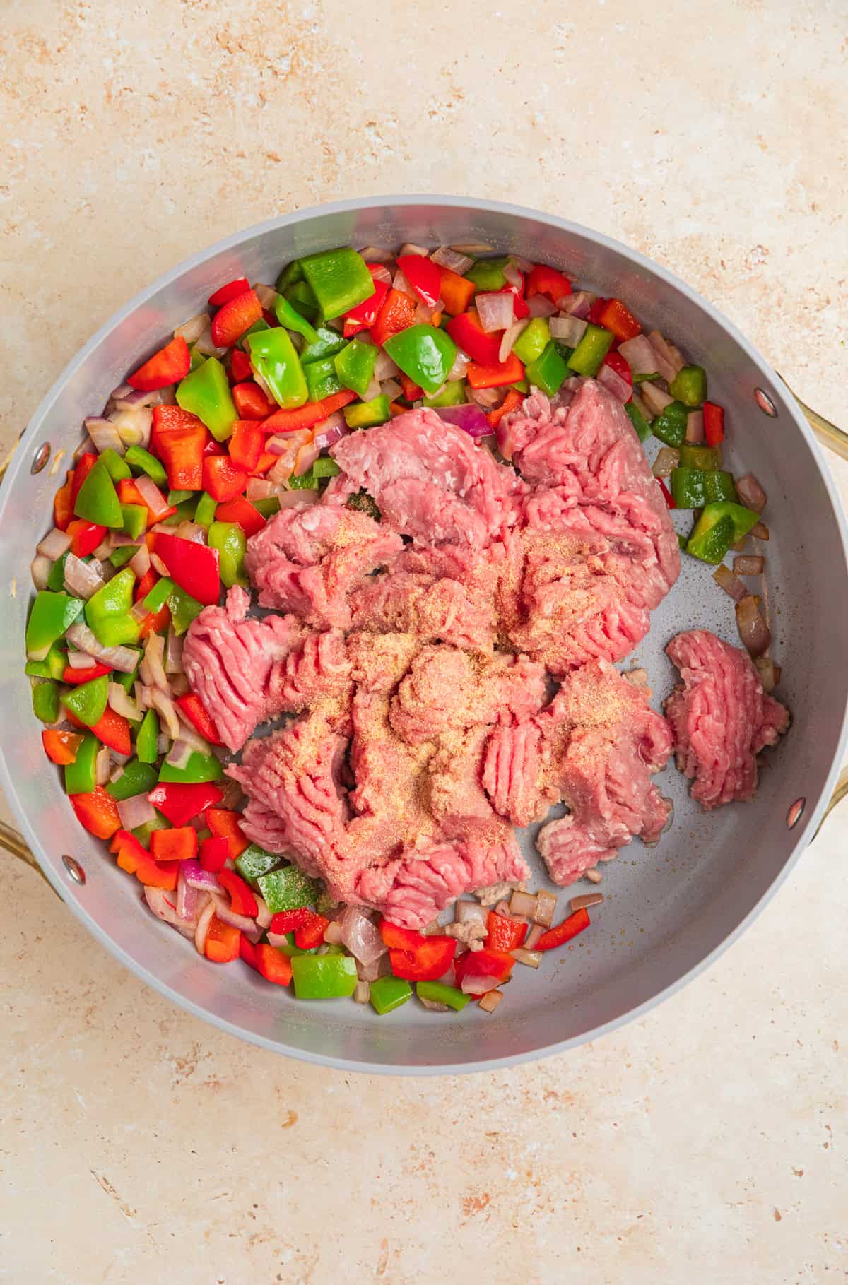 Ground turkey added to skillet with sautéed onions and peppers.