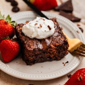 Piece of chocolate baked oats on plate with yogurt on top.