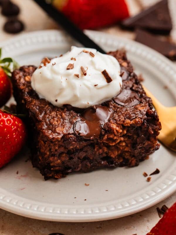 Piece of chocolate baked oats on plate with yogurt on top.