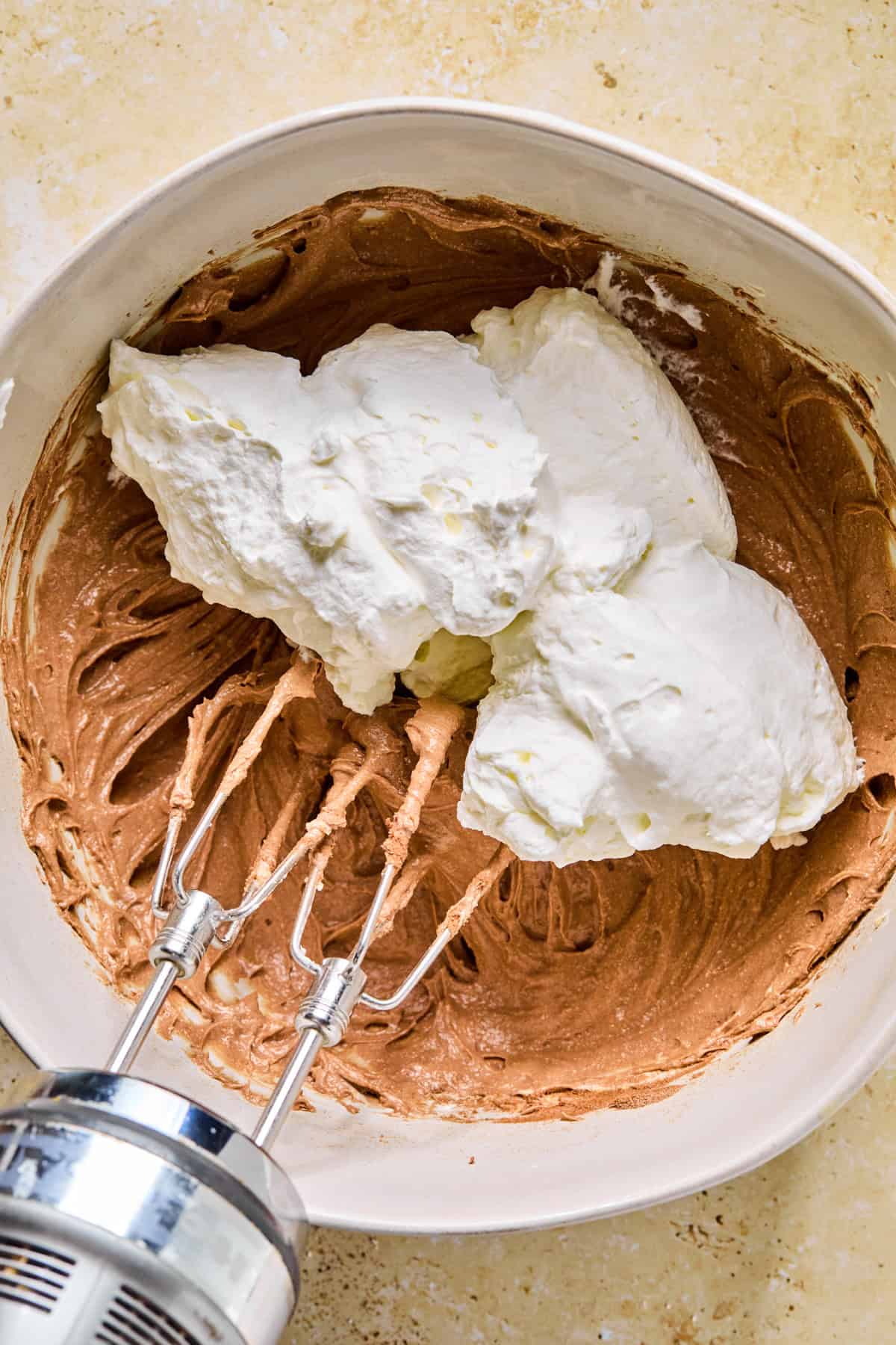 Cocoa cream cheese mixture with whipped cream dolloped into the bowl.