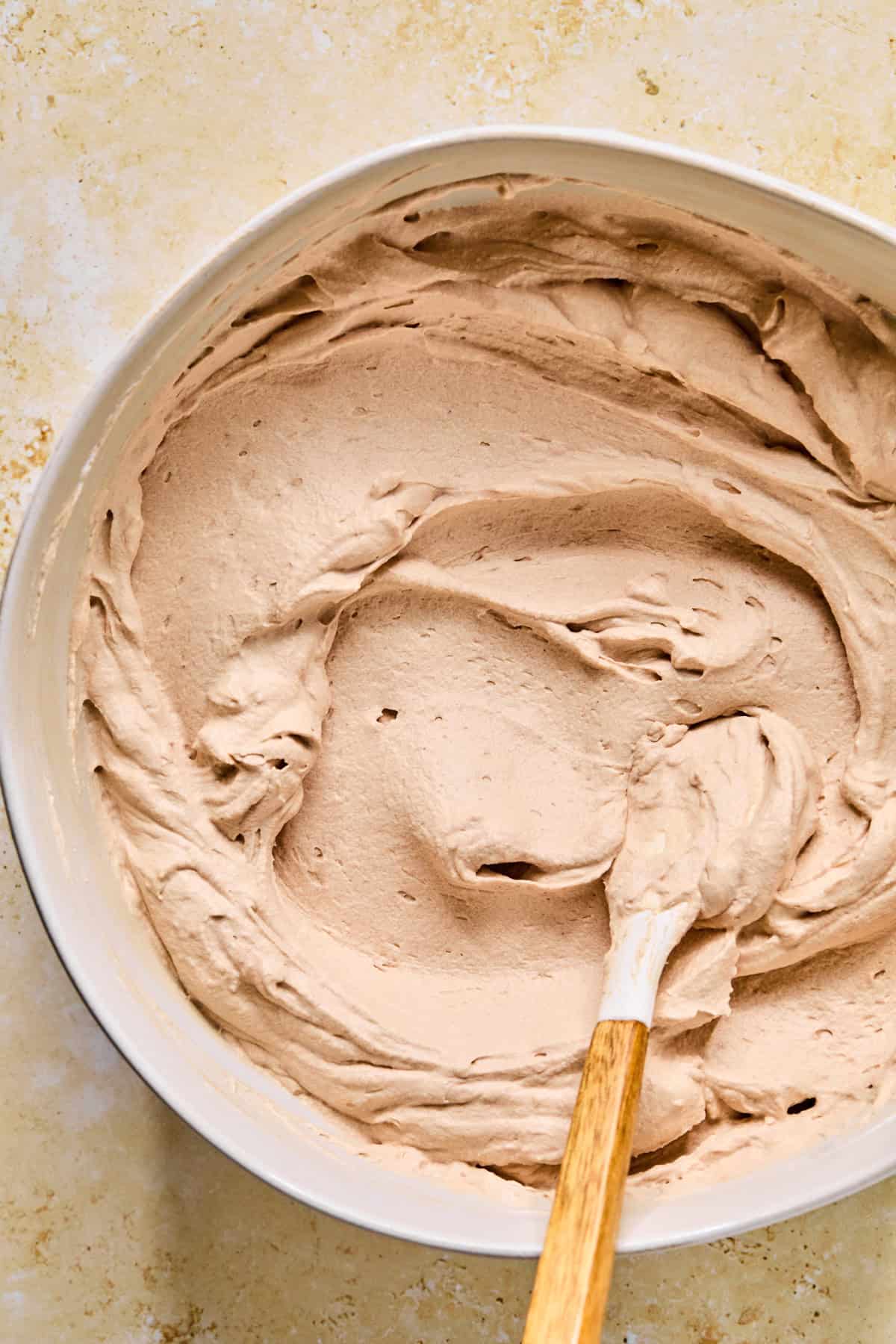 Creamy hot cocoa mixture with spatula in bowl.