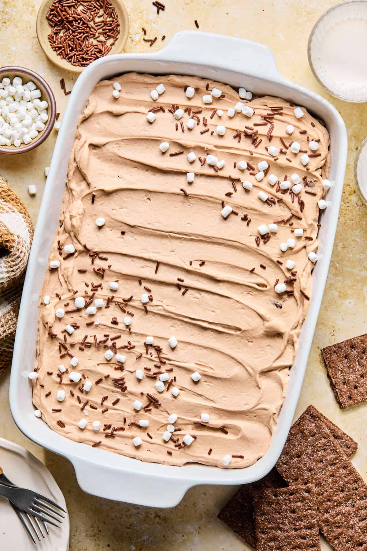 Hot cocoa icebox cake topped with mini marshmallows and chocolate sprinkles .