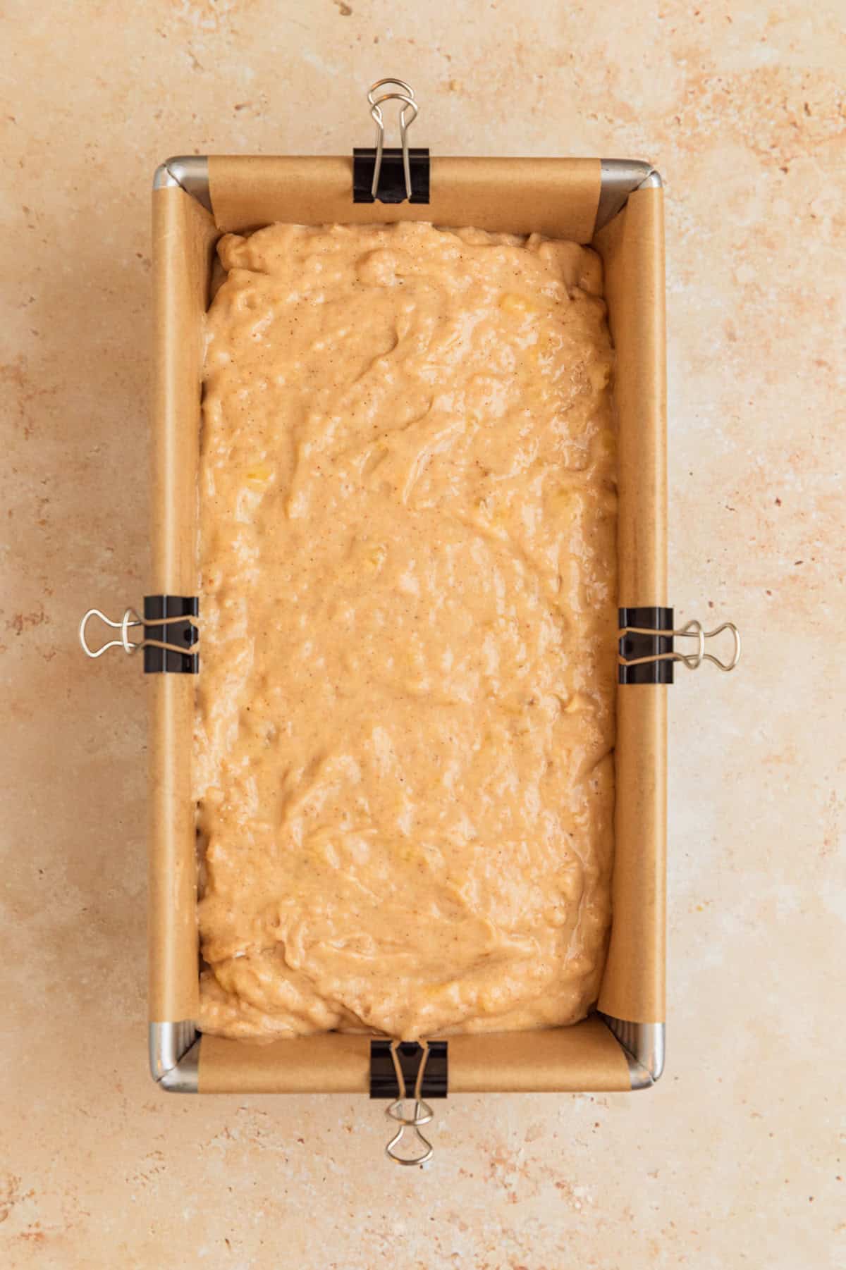 Banana bread batter in parchment lined bread pan.