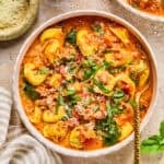 Crockpot sausage and tortellini soup in bowl with spoon.