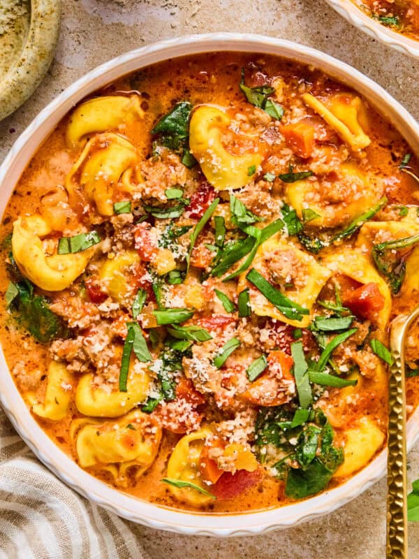 Crockpot sausage and tortellini soup in bowl with spoon.