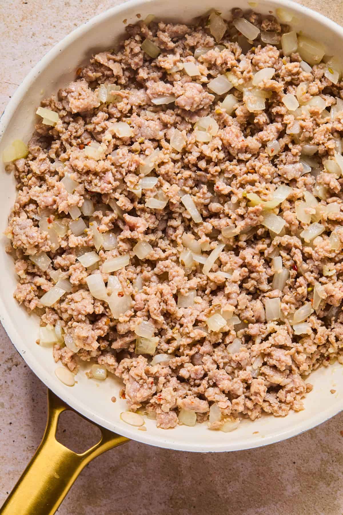 Browned Italian sausage in skillet with onions.