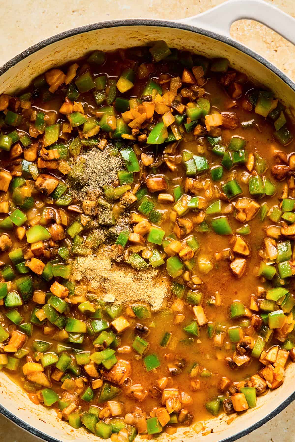 Seasonings added to skillet with cooked onions, peppers and mushrooms.