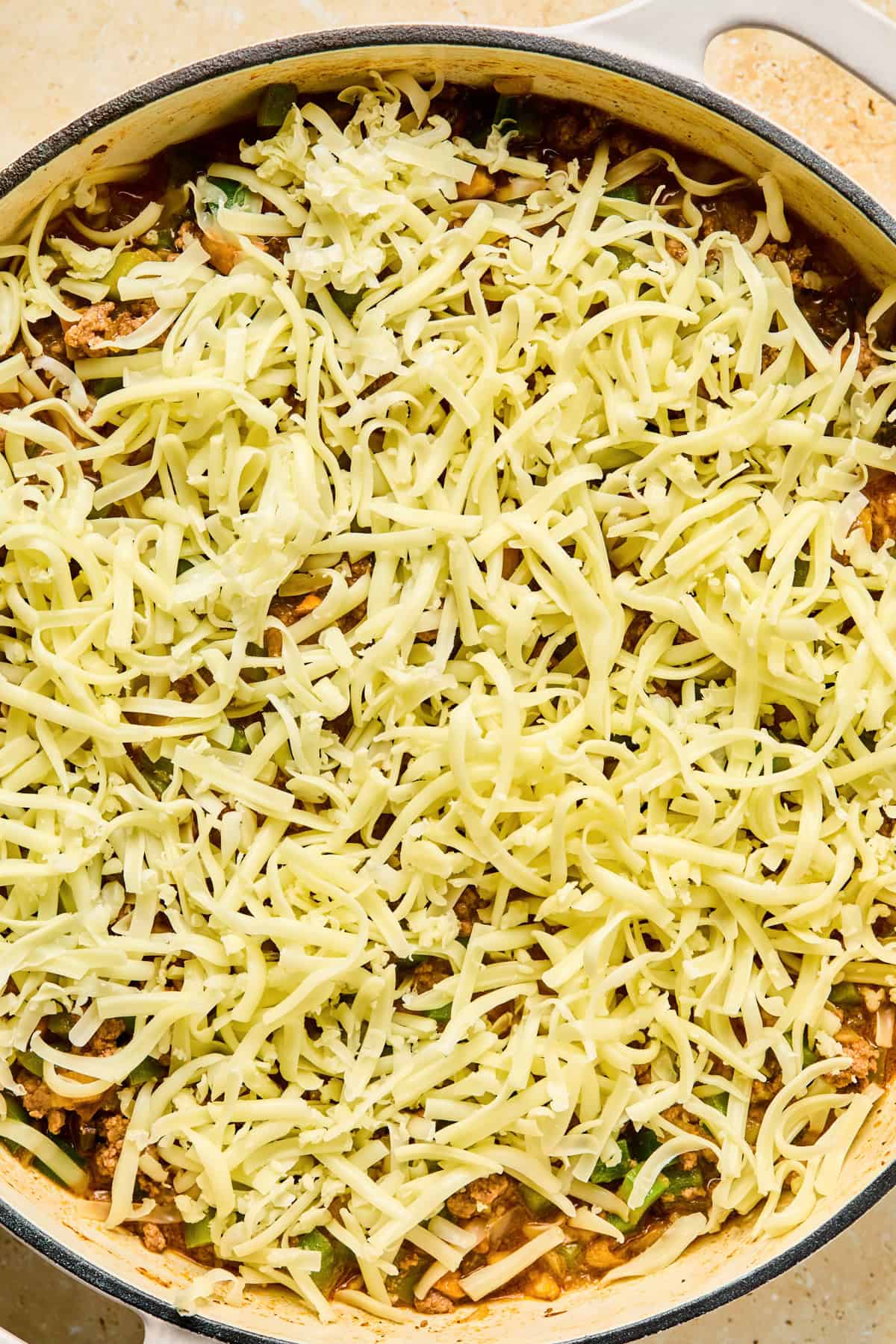 Shredded mozzarella cheese covering top of Philly cheesesteak skillet.