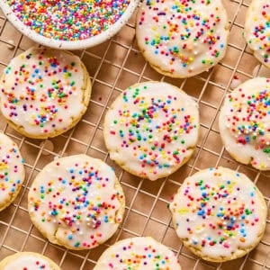 Iced sugar cookies on wire rack with sprinkles.