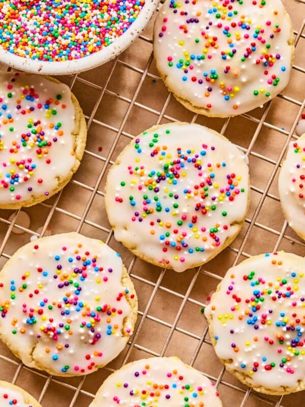 Iced sugar cookies on wire rack with sprinkles.
