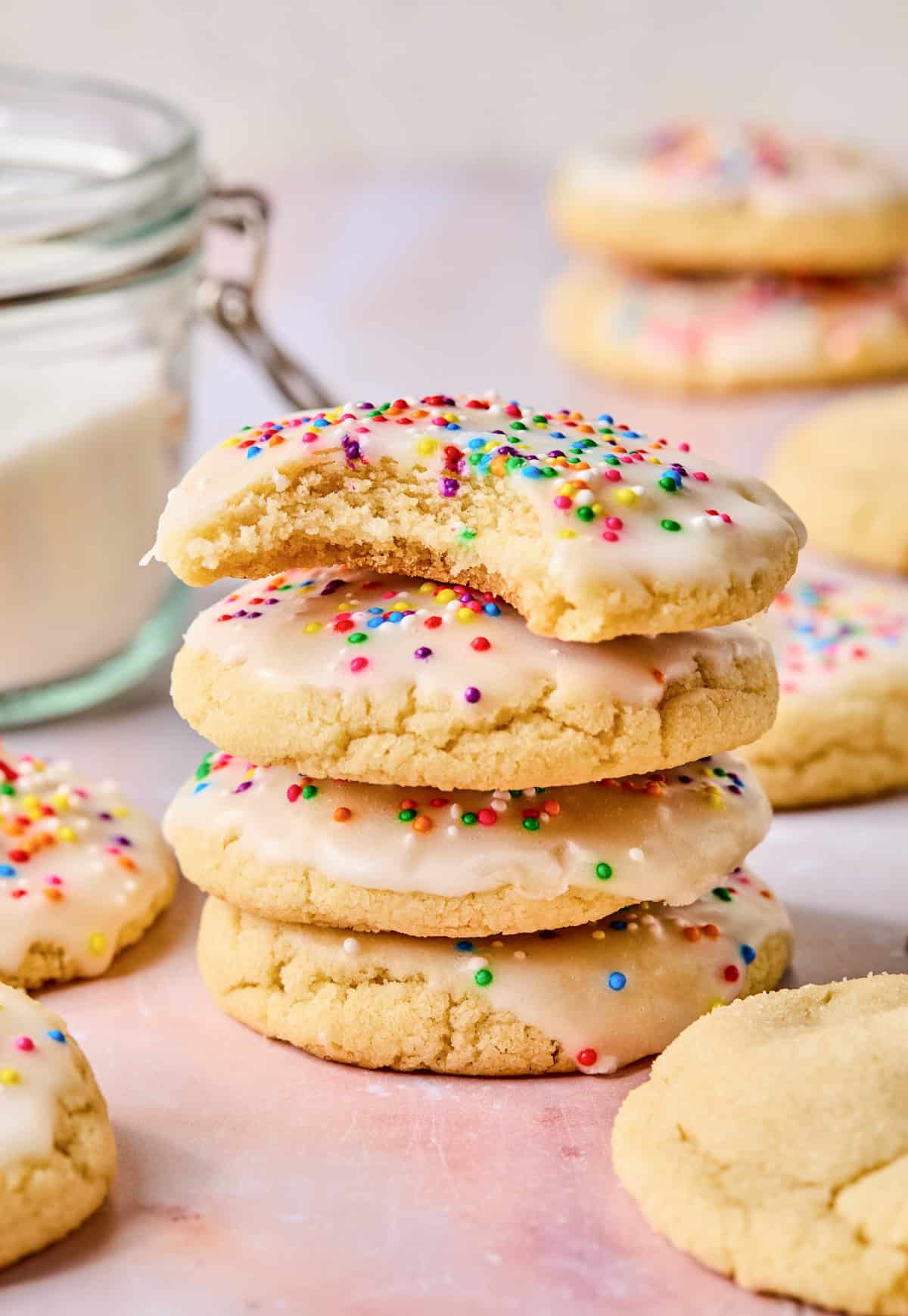 Stack of iced sugar cookies with bite taken out of top cookie.