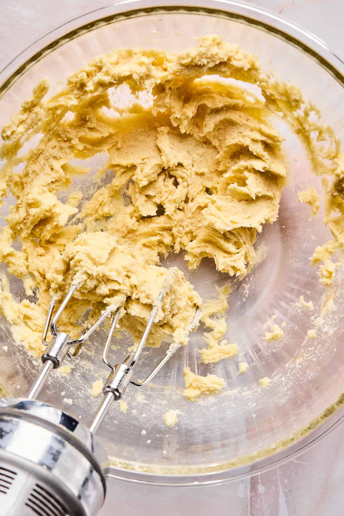 Egg, vanilla and almond extract mixed into butter and sugar in mixing bowl.