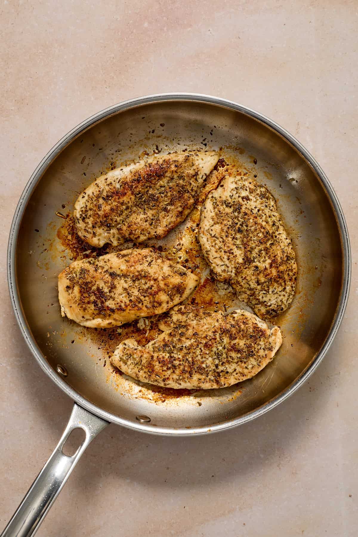 Seared chicken cutlets in skillet.