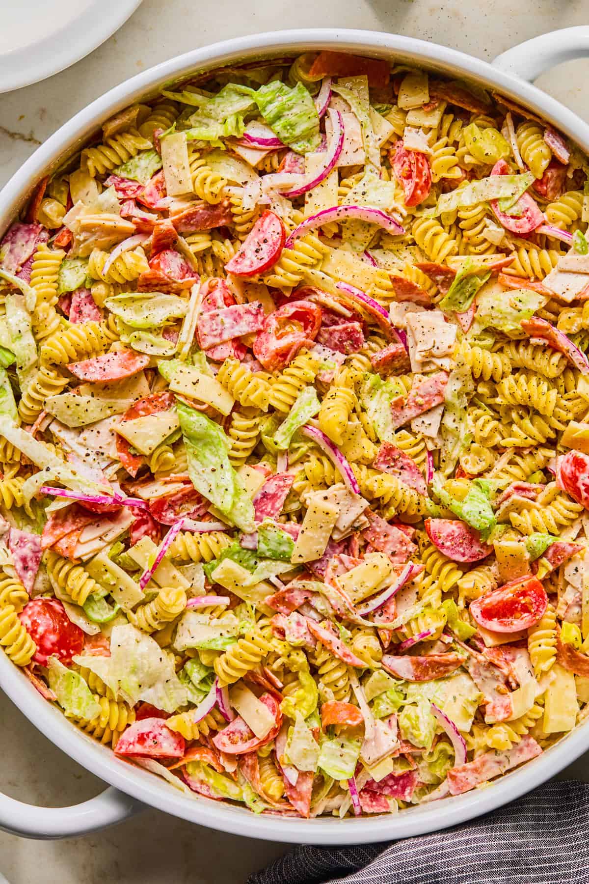 Pasta salad with turkey, pepperoni, salami, lettuce and other ingredients i serving bowl.