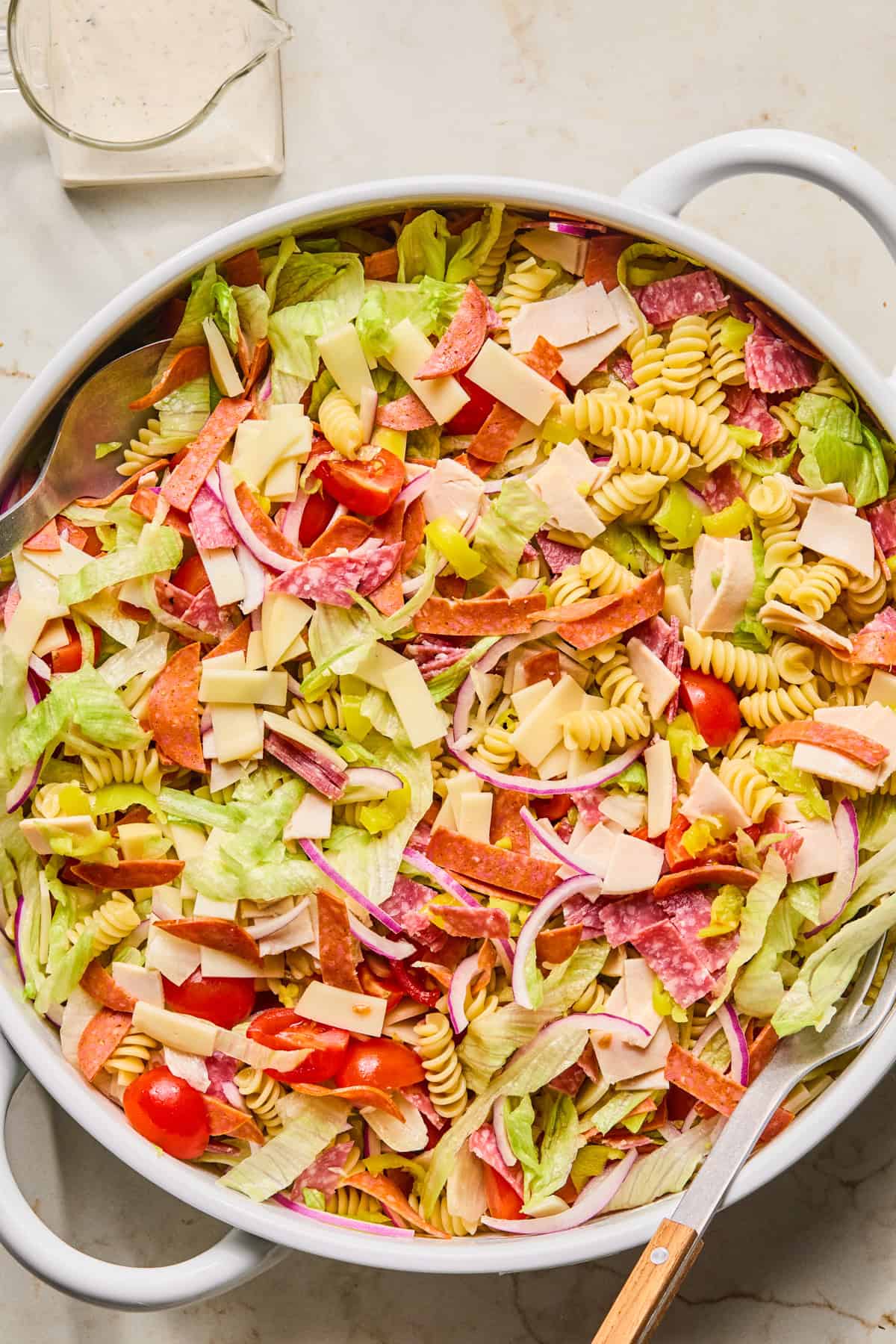 Grinder pasta salad ingredients in bowl tossed before adding dressing.