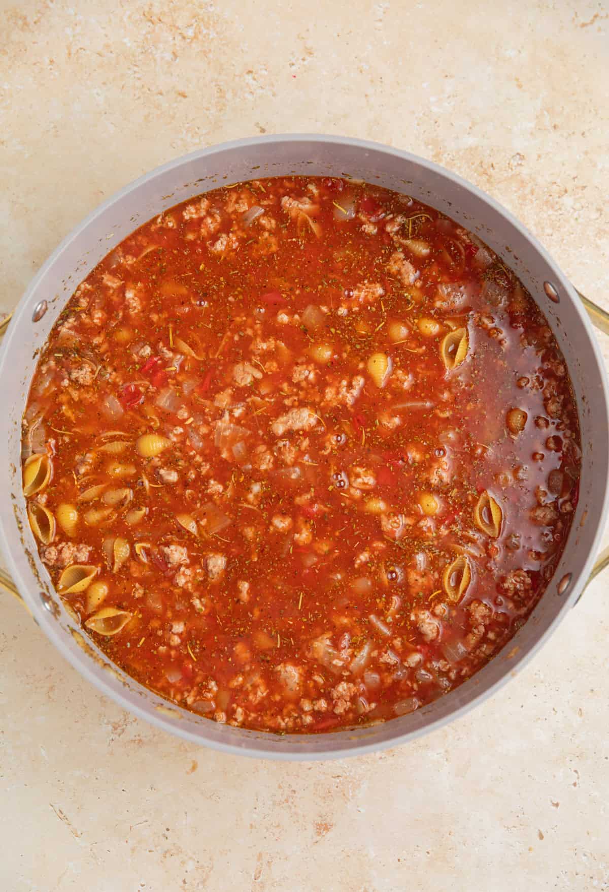 Pasta shells added to turkey, broth and tomato mixture in pan.