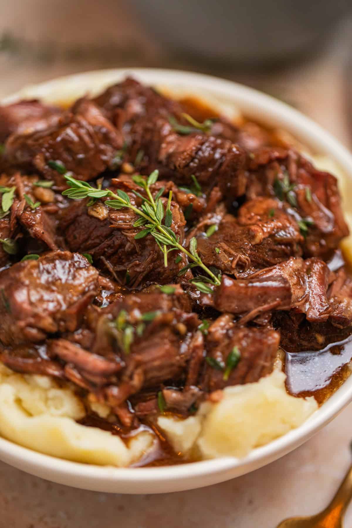 Mashed potatoes with chuck roast beef cubes and gravy topped with fresh thyme.