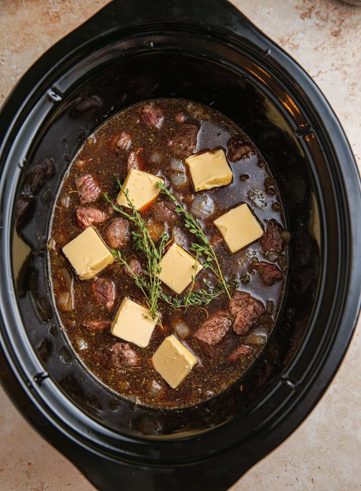 Butter and sprigs of thyme over top of beef tips in crock pot.