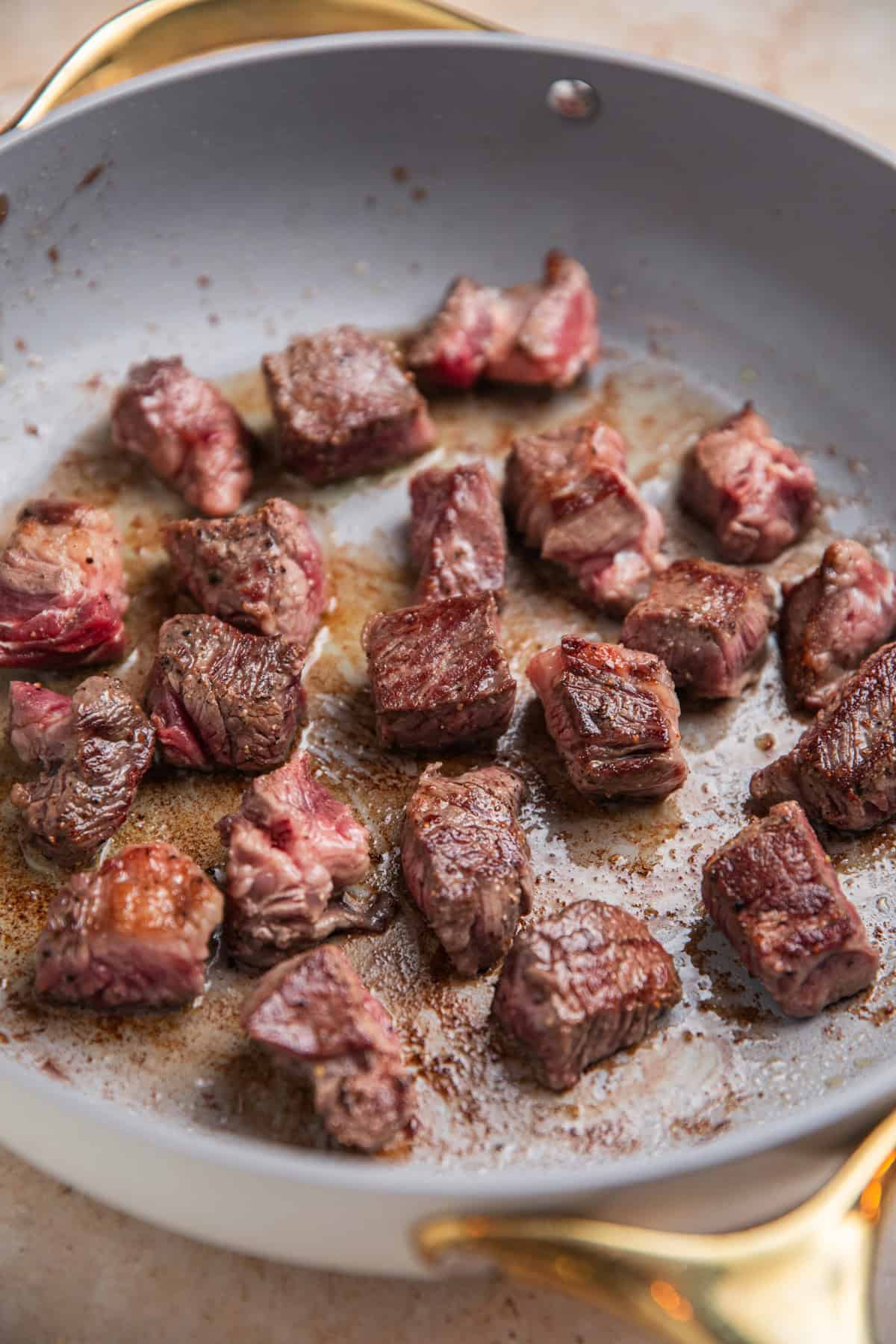 Seared beef cubes in skillet.