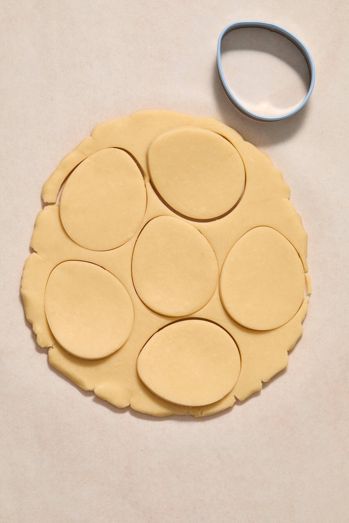 Cookie dough rolled out with egg cookie cutter pressed into it.