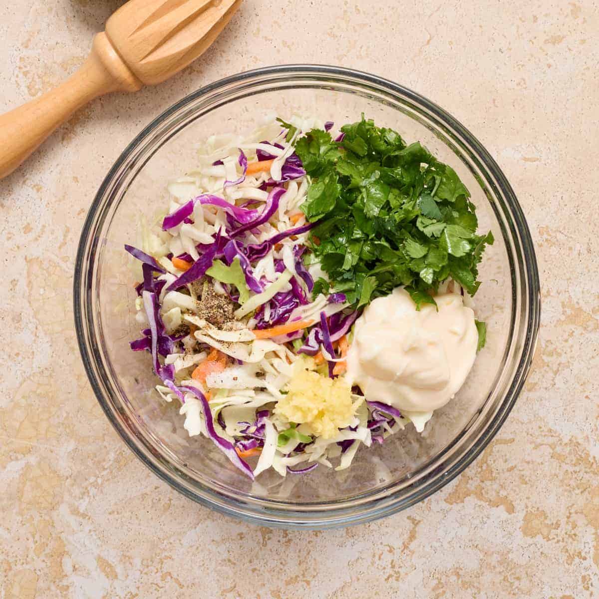 Cilantro lime slaw ingredients in glass mixing bowl.